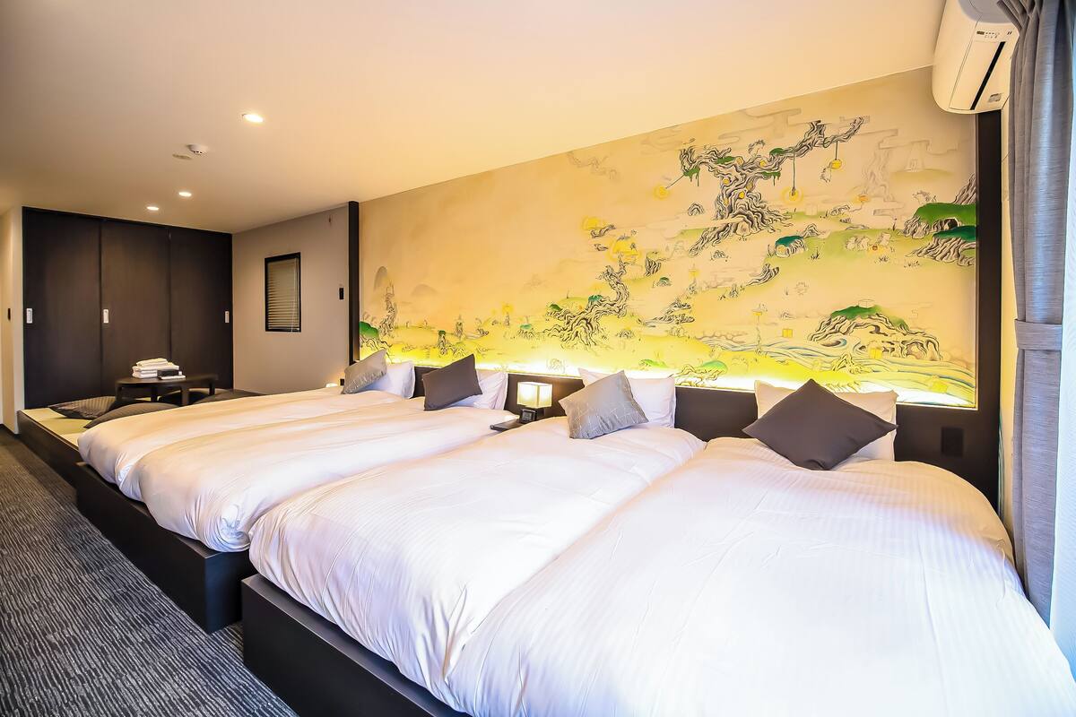 Una habitación de hotel con una cama grande, un mural en la pared y una ventana con cortinas.