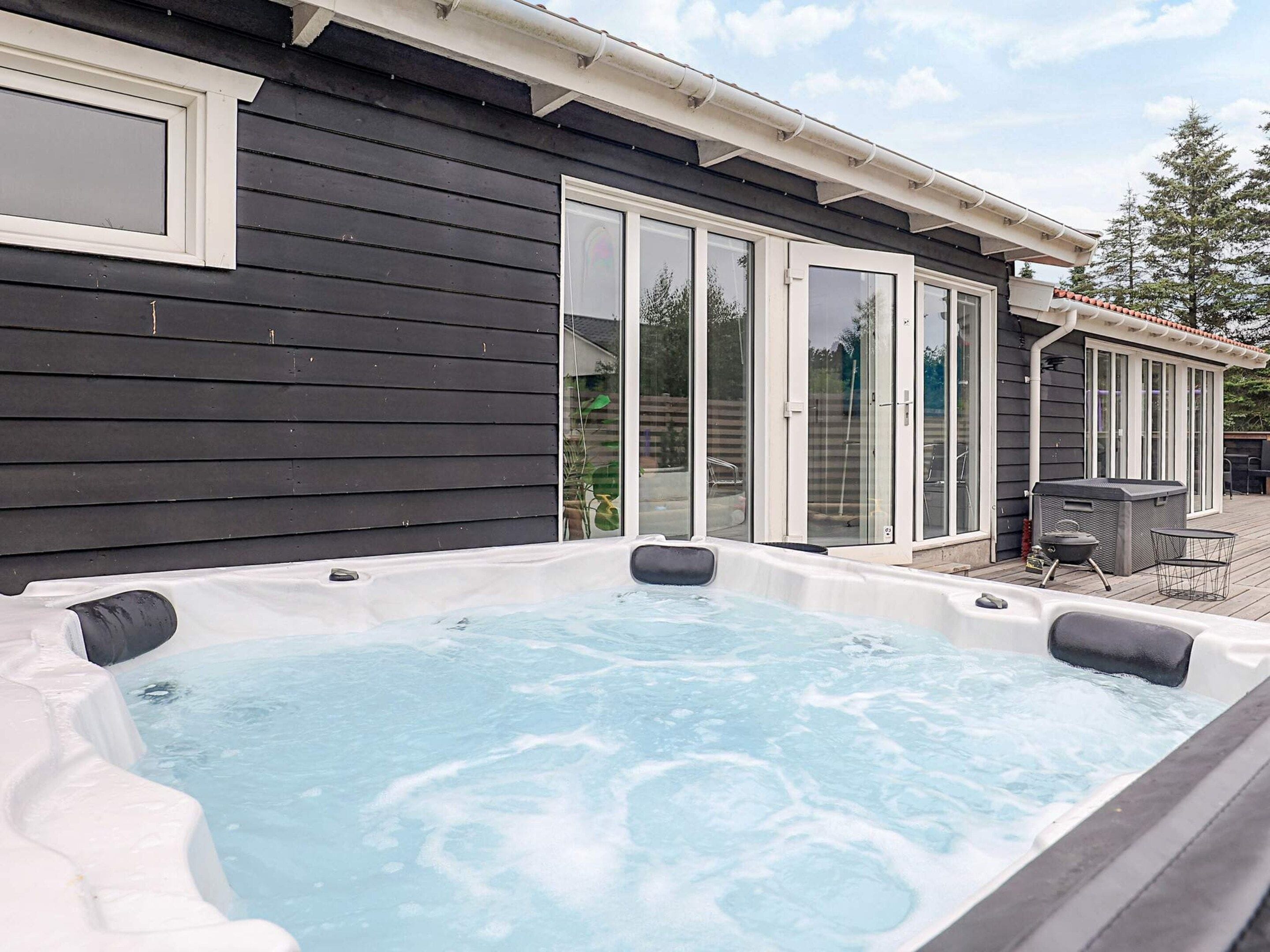 A hot tub in a backyard with a sliding glass door and a patio area.