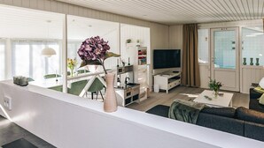 A modern living room with a sofa, a coffee table, a TV, and a vase with flowers. - 4 Star Holiday Home in Vaeggerlose (Vaeggerlose)