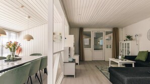 A modern living room with a dining area, featuring a white ceiling, wooden flooring, and a black sofa. - 4 Star Holiday Home in Vaeggerlose (Vaeggerlose)