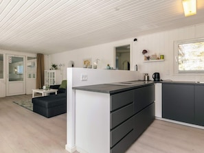 A modern kitchen with a white and dark grey color scheme, a built-in stove, and a window with blinds. - 4 Star Holiday Home in Vaeggerlose (Vaeggerlose)