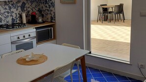 A modern kitchen with white cabinets, a dining table with a woven placemat, and a blue-tiled floor. - AB Apartment (Ragusa)