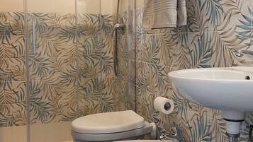 Un baño con ducha, inodoro, bidé y lavabo.