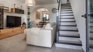 A modern living room with a sofa, TV, and staircase.