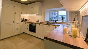 A modern kitchen with white cabinets, a wooden countertop, and a window with a view of the outdoors. - Renovated country chic cottage, 6 bedrooms for 13, garden, terrace, Haute-Loire (Siaugues-Sainte-Marie)