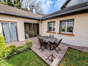 Une terrasse avec une table et des chaises, une porte-fenêtre coulissante et un mur en briques.
