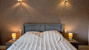 A bedroom with a bed, two bedside lamps, and a textured wall.