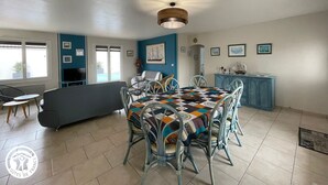 A dining area with a table set for four, surrounded by chairs, a sofa, and a television. - Family cottage with heated pool in Bretignolles-sur-Mer (Bretignolles-sur-Mer)