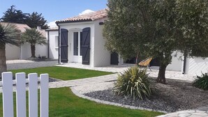 A residential property with a white exterior, a stone pathway, a fenced yard, and a small tree. - Family cottage with heated pool in Bretignolles-sur-Mer (Bretignolles-sur-Mer)