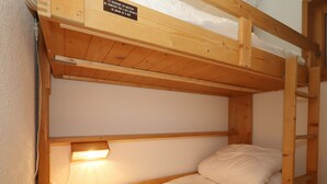 A bunk bed with a wooden headboard and a small shelf above it. - 2-room cabin apartment in Les Houches, 6 guests, pets welcome (Les Houches)