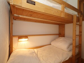 Een stapelbed met een houten hoofdbord en een klein plankje erboven.