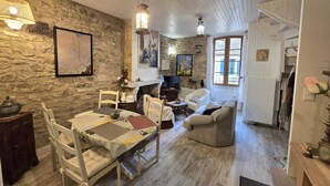 Een gezellige woonkamer met een stenen muur, een open haard en een eethoek met een tafel en stoelen.