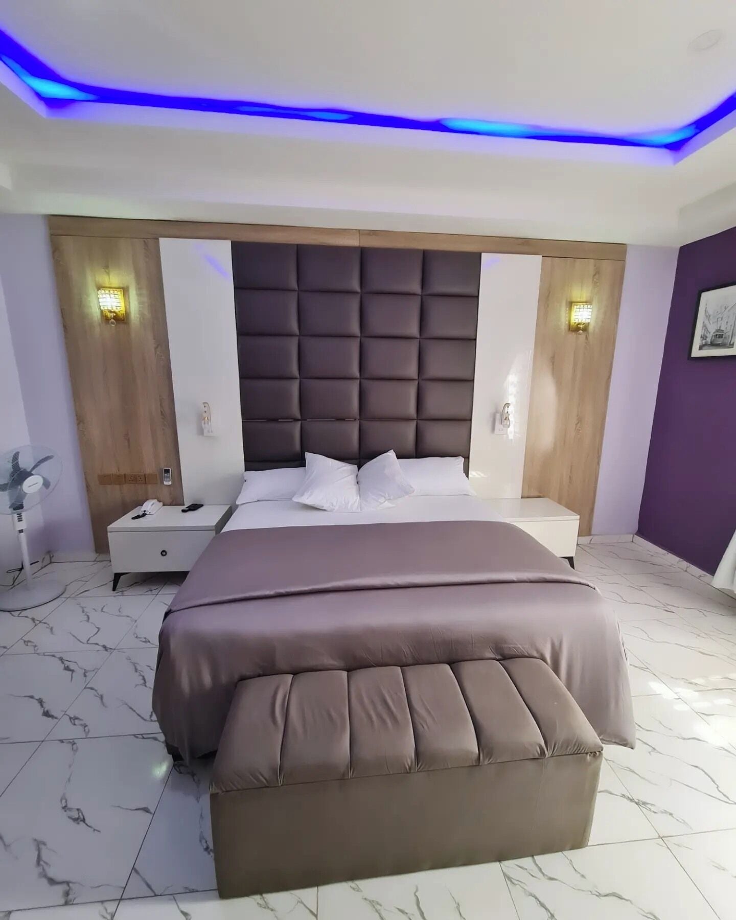 Une chambre à coucher moderne avec un grand lit, une tête de lit en bois et un sol carrelé en marbre.