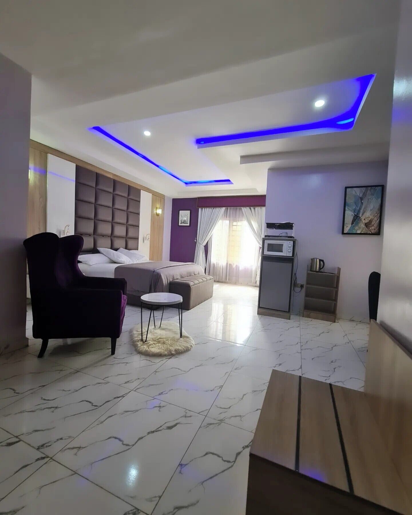 A modern hotel room with a bed, a sofa, a small round table, and a microwave.