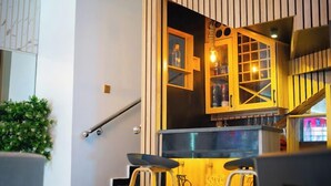 A modern interior with a staircase, a bar area with stools, and a decorative wall with shelves. - Uphoria Apartments (Abuja)