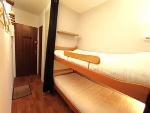 A small, compact room with two bunk beds, a wooden door, and a small shelf. - Studio Cabin 6 Pax, Balcony Near Slopes, St Lary Soul. (Saint-Lary-Soulan)