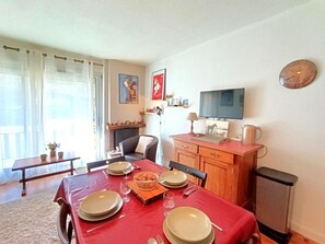 A dining area with a red tablecloth, a fireplace, a television, and a clock on the wall. - Studio Cabin 6 Pax, Balcony Near Slopes, St Lary Soul. (Saint-Lary-Soulan)