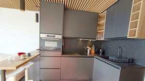 Une cuisine compacte dotée d’appareils électroménagers modernes, d’un four encastré et d’un évier.