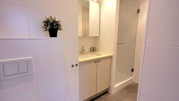 Een moderne badkamer met witte tegels, een wastafel, een spiegel en een douchecabine.