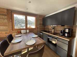 A modern kitchen with wooden cabinetry, a built-in oven, and a coffee maker.