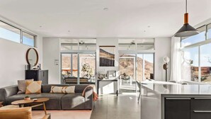 A modern kitchen with a large island, a dining area with a view, and a living room with a sofa and coffee table.