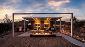 A modern outdoor living area with a fire pit, seating, and a covered patio.