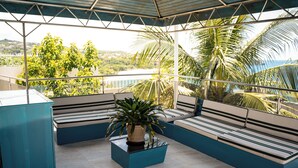 Een balkon met een zithoek, een bloempot en uitzicht op groen en een waterpartij.