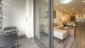 A modern interior with a glass door leading to a living area, a dining area, and a kitchenette. - Luxe Paradise Suites Tay Ho (Hanoi)