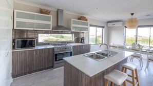 Una cocina moderna con una isla central, electrodomésticos de acero inoxidable y vistas al exterior.