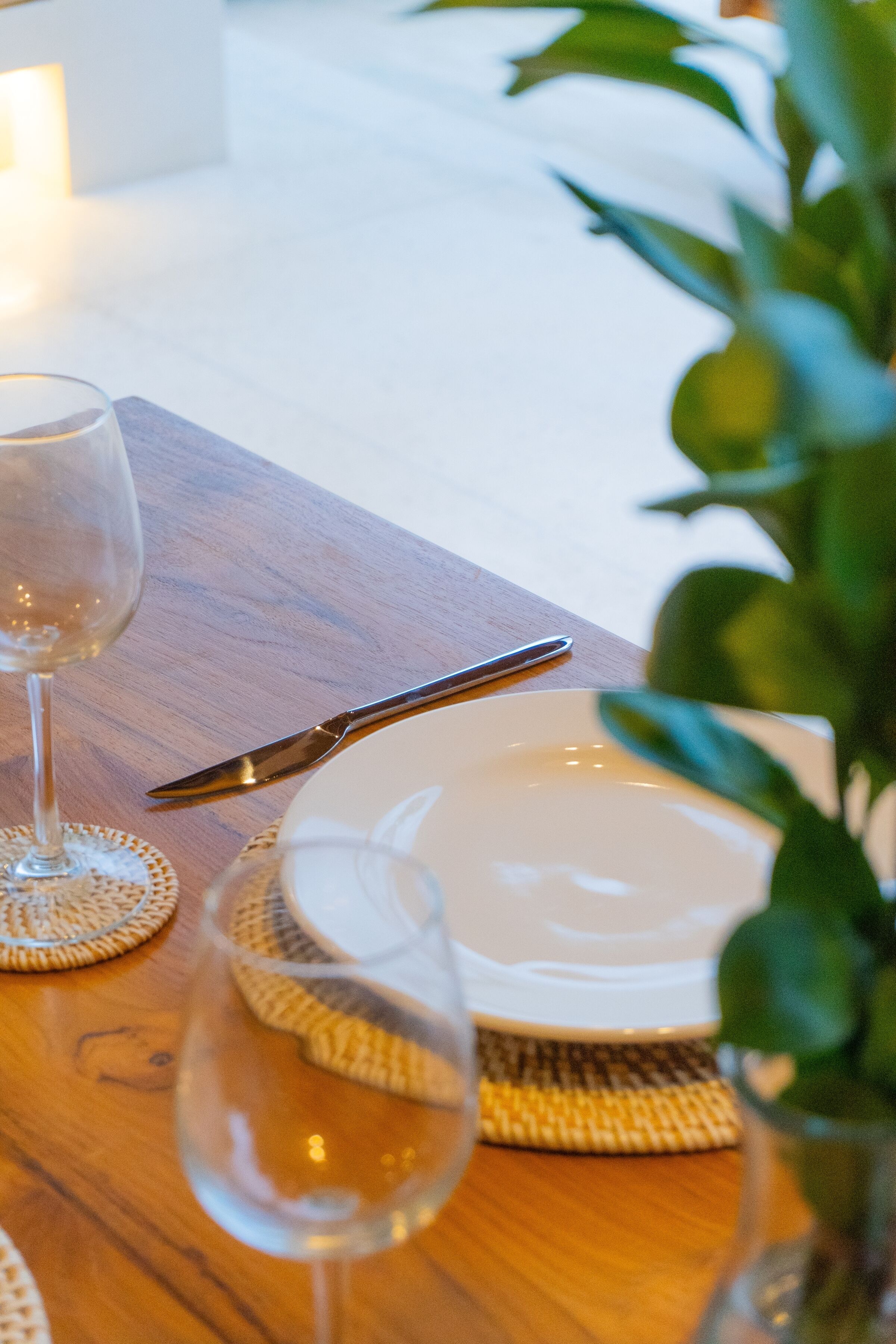 A dining table with a plate, a knife, and a glass of water.