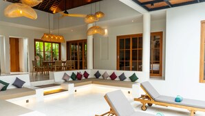 Un espace de détente moderne comprenant un grand coin salon, une table à manger et deux chaises longues.