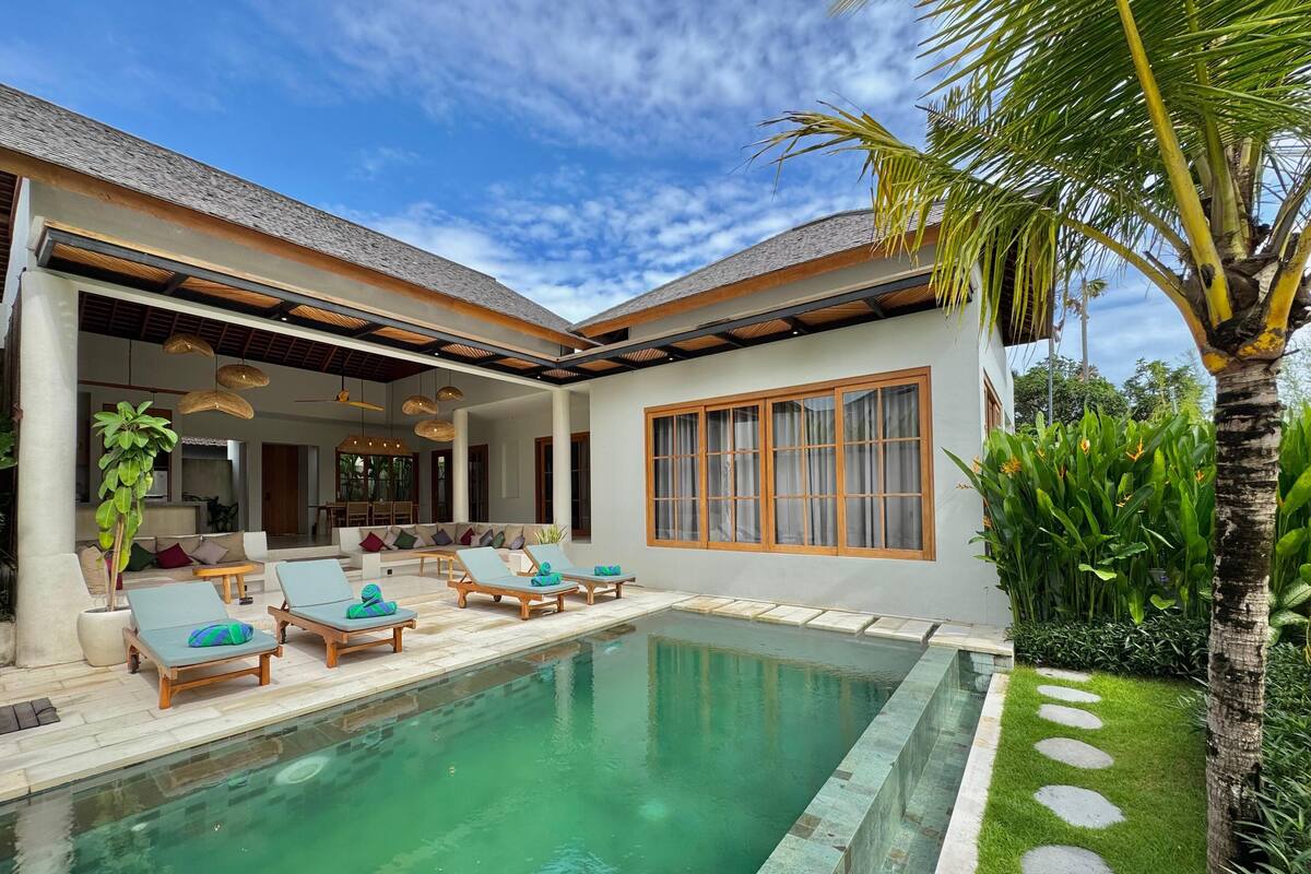 A modern house with a swimming pool, outdoor seating, and lush greenery.