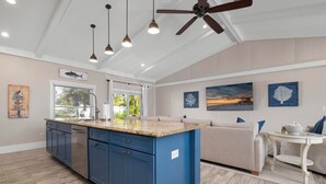 A spacious kitchen with blue cabinets, a large island, and pendant lighting. - Cocktails and Dreams by Beach Boutique Rentals (Holmes Beach)