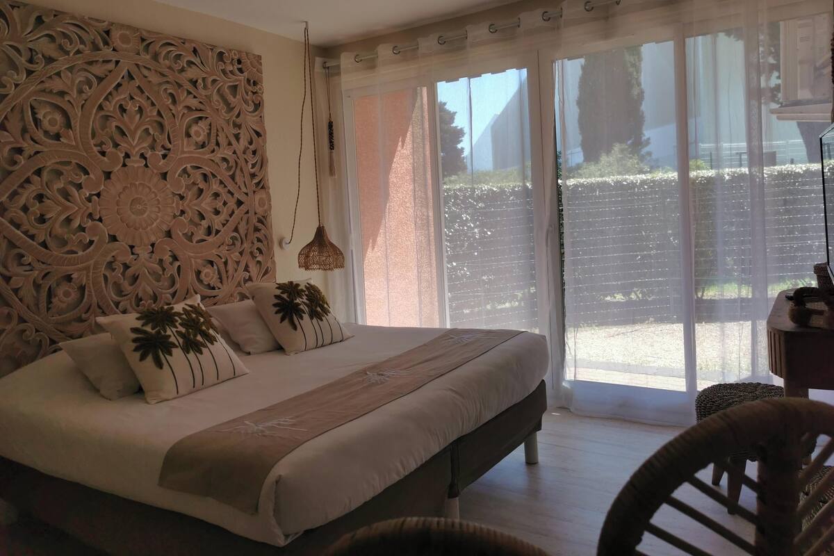 Una camera da letto con un letto grande, una parete decorativa, una lampada a sospensione e vista attraverso una porta scorrevole in vetro.