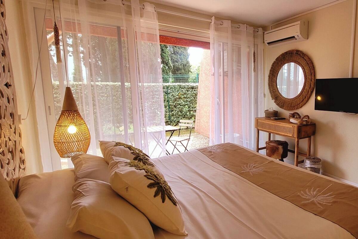 Una camera da letto con un letto, una TV, uno specchio e una finestra con tende.