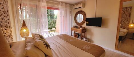 Une chambre à coucher avec un lit, une télévision, un miroir et une fenêtre avec des rideaux.