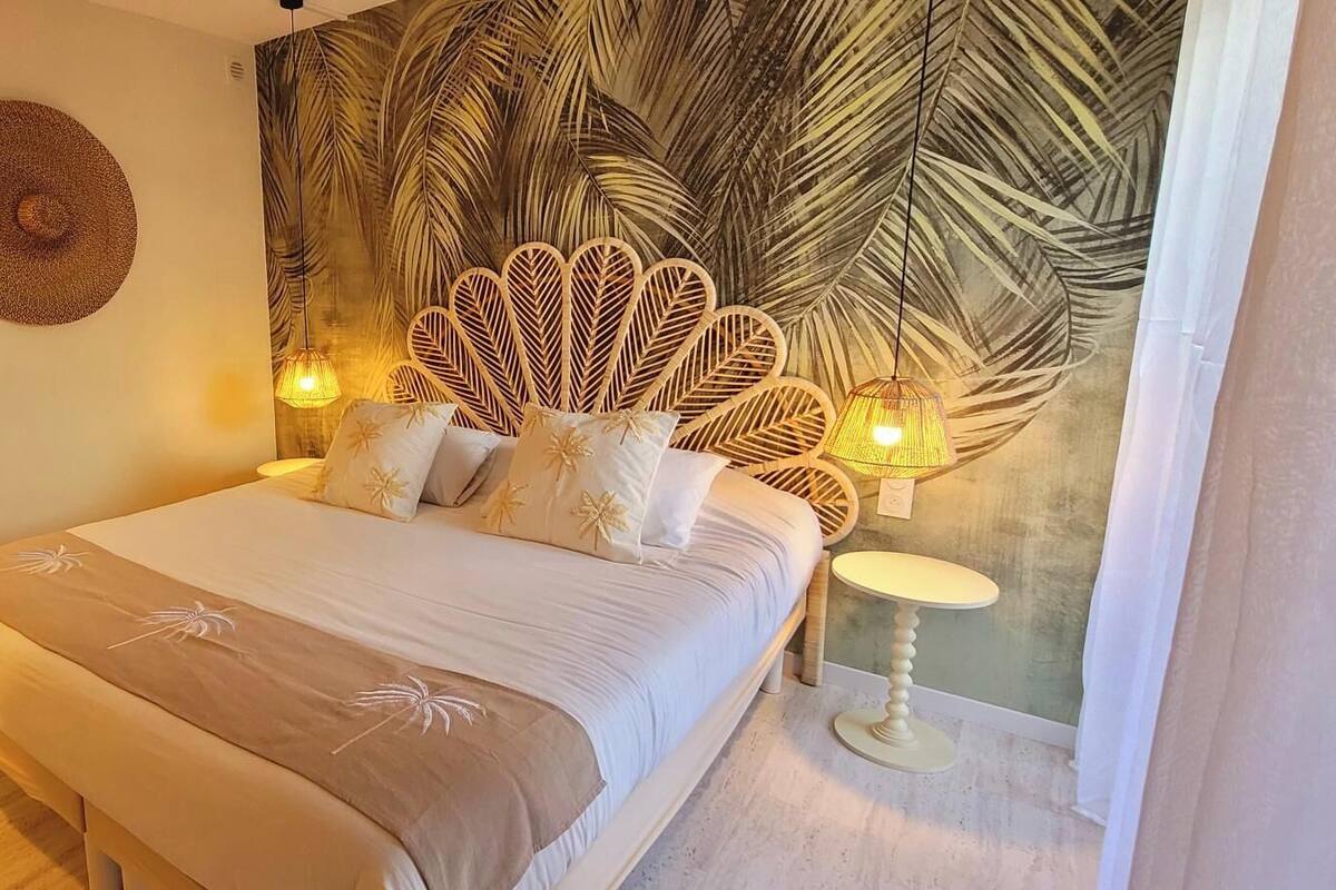 Camera da letto con un letto, una testiera, un affresco, un comodino e una lampada.
