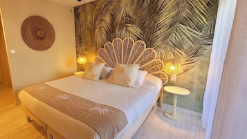 Een slaapkamer met een bed, hoofdeinde, muurschildering, nachtkastje en een lamp.