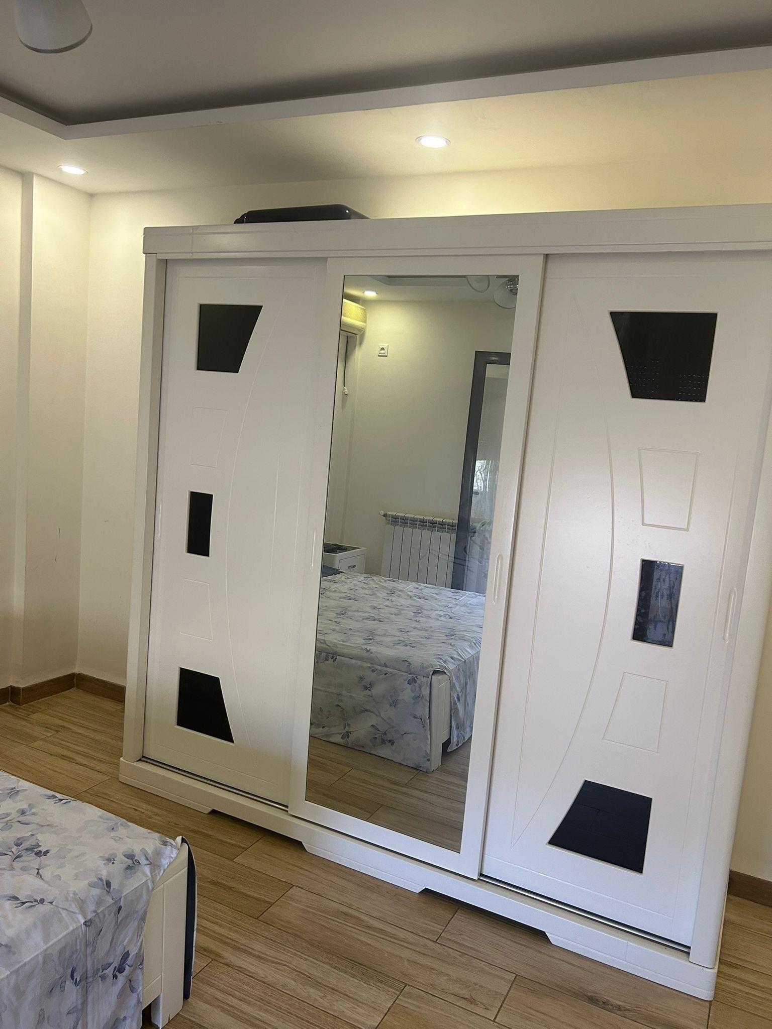 Een slaapkamer met een grote garderobe, een bed met een bloemenbedekking en een nachtkastje.