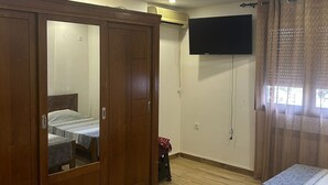 Camera da letto con armadio, un letto, una TV e una lampada a soffitto.