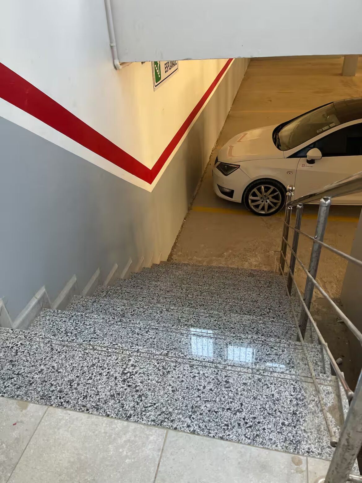 Un parking où une voiture blanche est garée dans une place marquée « ESPALDA ».