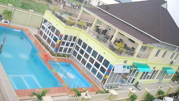 A two-story building with a swimming pool, large windows, and a balcony. - Aaliyah Royale Hotel  (Abuja)