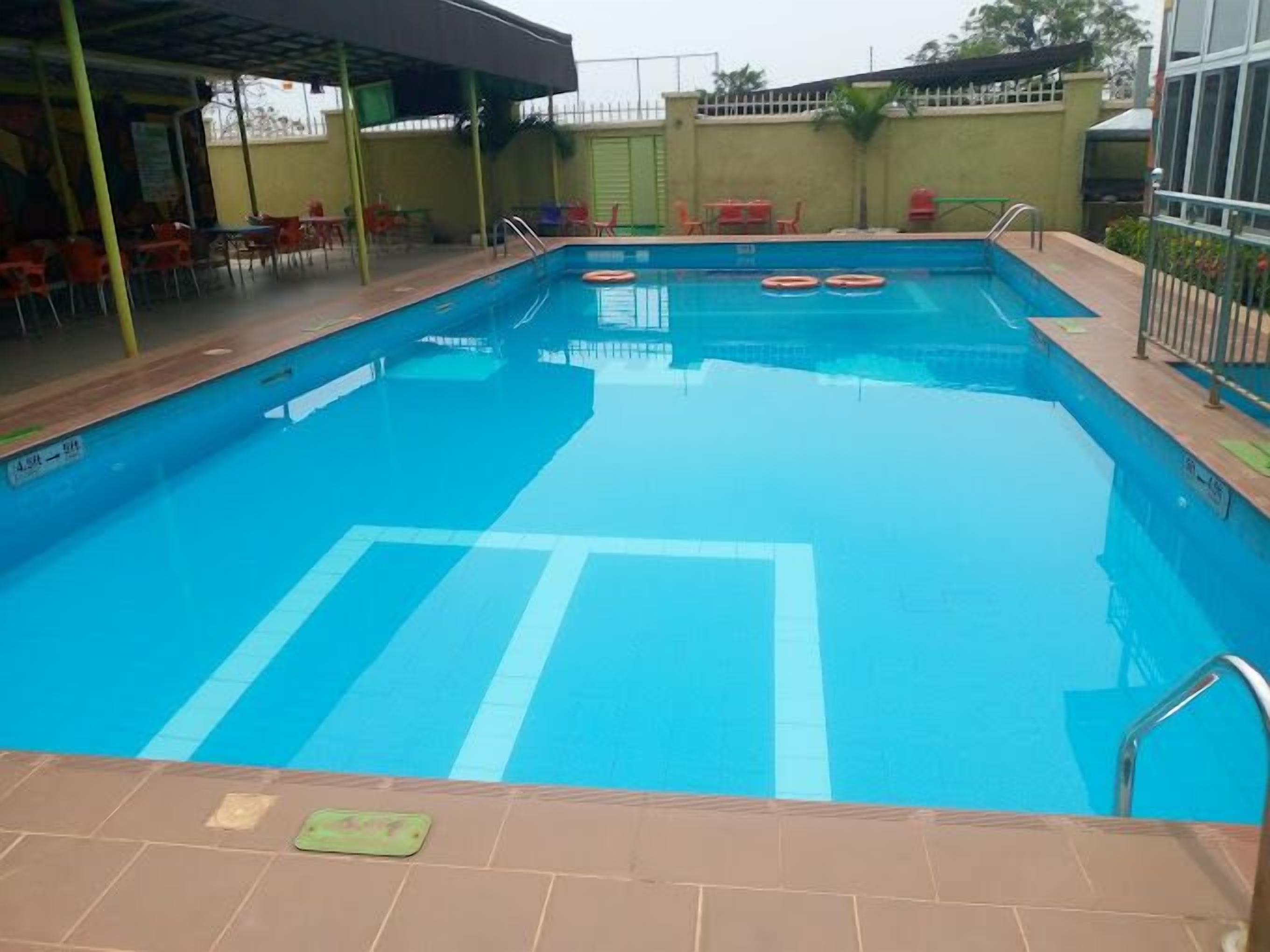 A swimming pool with clear blue water, surrounded by a tiled deck.