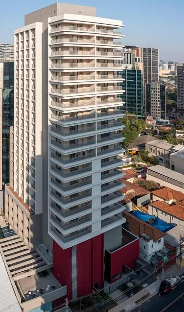 A high-rise building with multiple balconies, surrounded by other buildings and a clear sky. - Studio Next One Faria Lima (São Paulo)