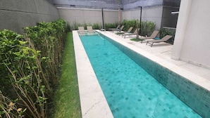 Una piscina rettangolare con acqua cristallina, circondata da un muretto e da una fila di sdraio.