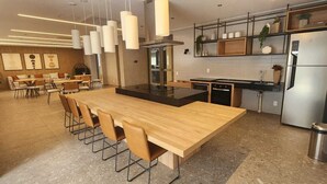 Una cucina moderna con isola centrale, elettrodomestici in acciaio inossidabile e zona pranzo con un lungo tavolo in legno e sedie.