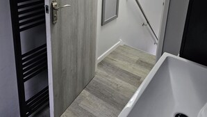 A bathroom with a white sink, a door with a handle, and a mirror on the wall. - Beach house in pembrokeshire with sea views (Freshwater East)