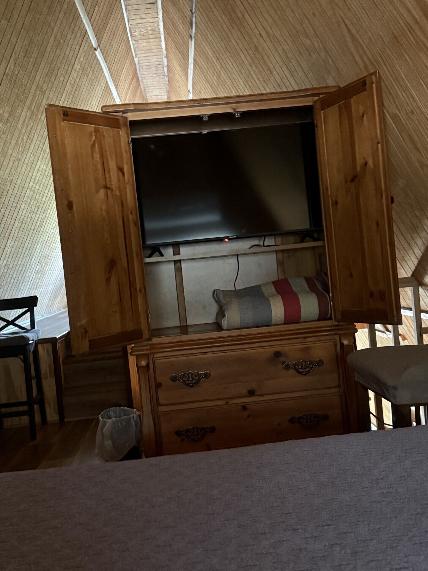 Un intérieur en bois avec un grand téléviseur à écran plat, une commode en bois et un fauteuil.