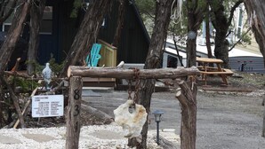 Ein rustikaler Außenbereich mit Holzkonstruktion, einem Schild mit Wetterinformationen und einem großen Felsen als Blickfang.
