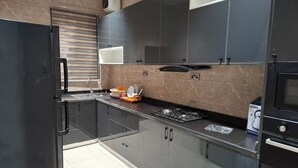 A modern kitchen with stainless steel appliances, a built-in oven, and a gas stove. - DEOSEA APARTMENTS (Abuja)